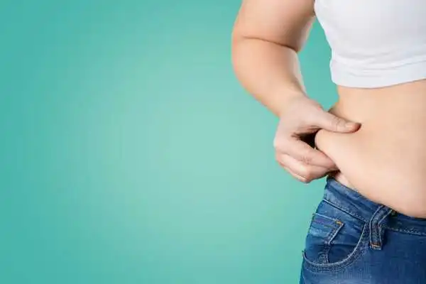 Image of woman pinching her love handles to show weight gain West End
